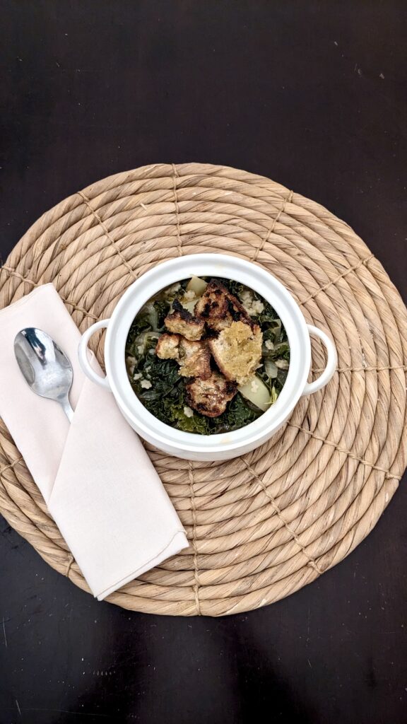 soup bowl with croutons on top, spoon and napkin on the side all sitting on a placemat