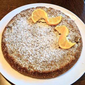 Lemon cake with powdered sugar and lemon slices on top on white plate