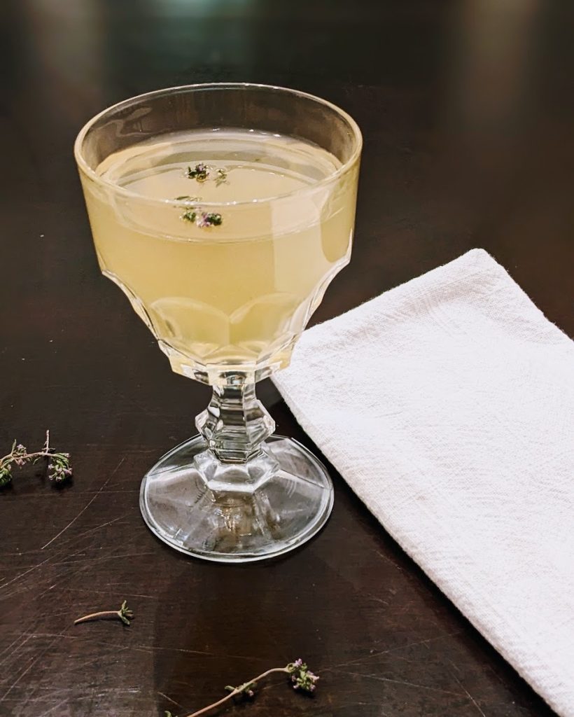 glass of thyme blossom lemonade with thyme blossom sprig on top