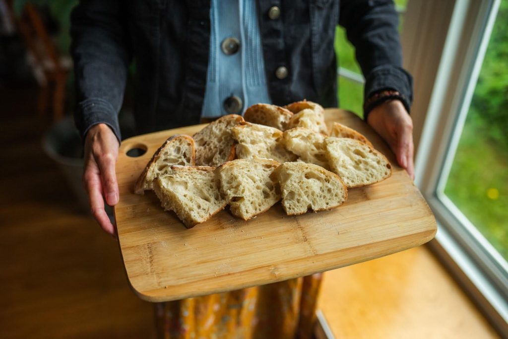 woman holding sourdough bread on a cutting board