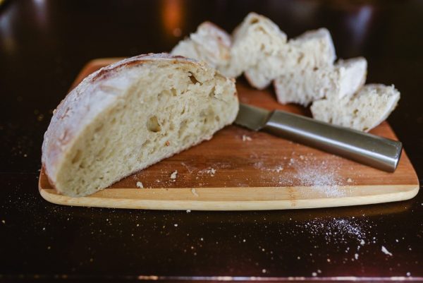 loaf of artisan sourdough bread on cutting board with knife