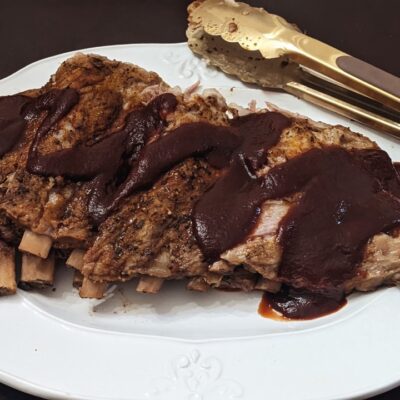 ribs with bbq sauce on a white plate and gold tongs