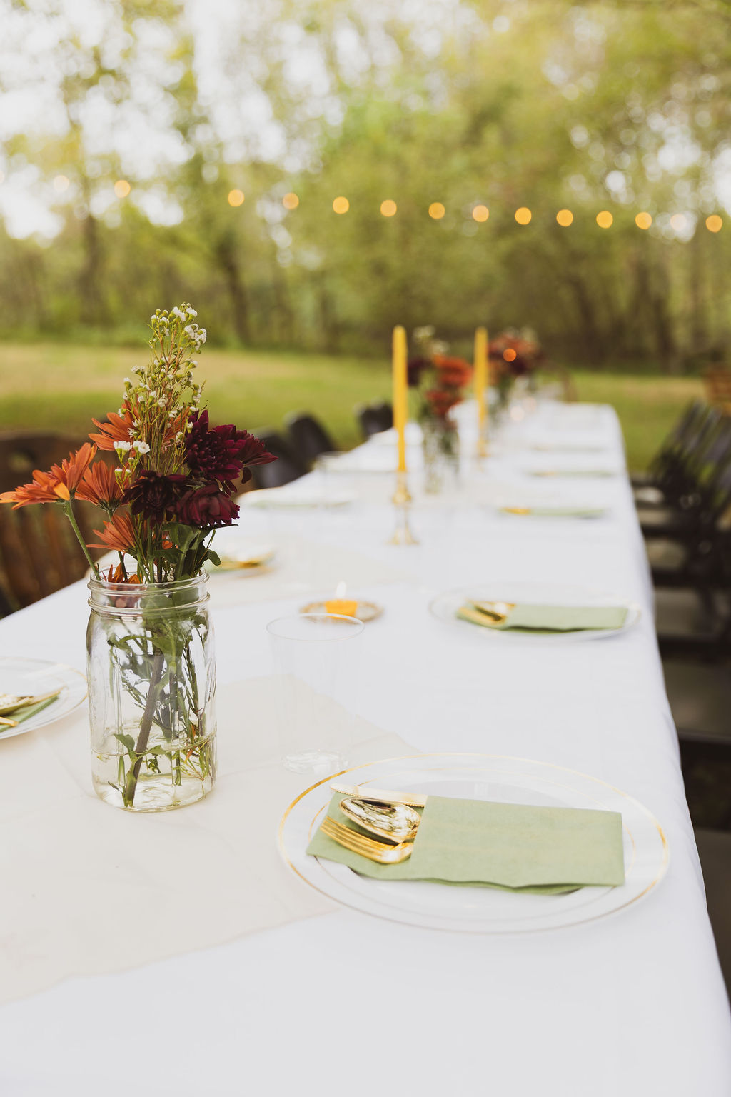 white table with place settings and simple flower centerpieces